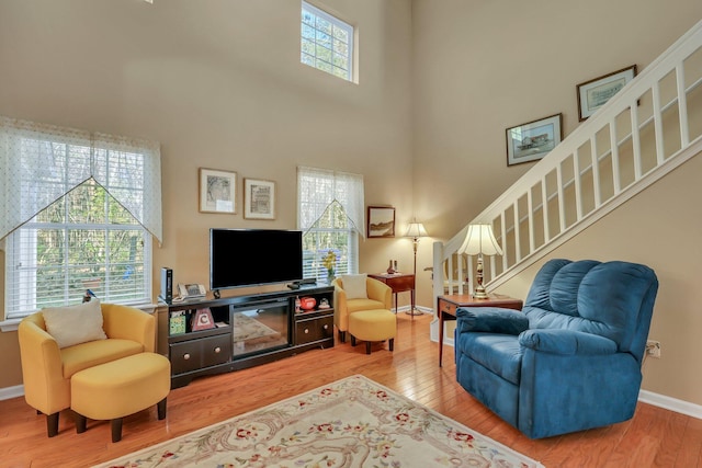 living room with a towering ceiling and wood-type flooring