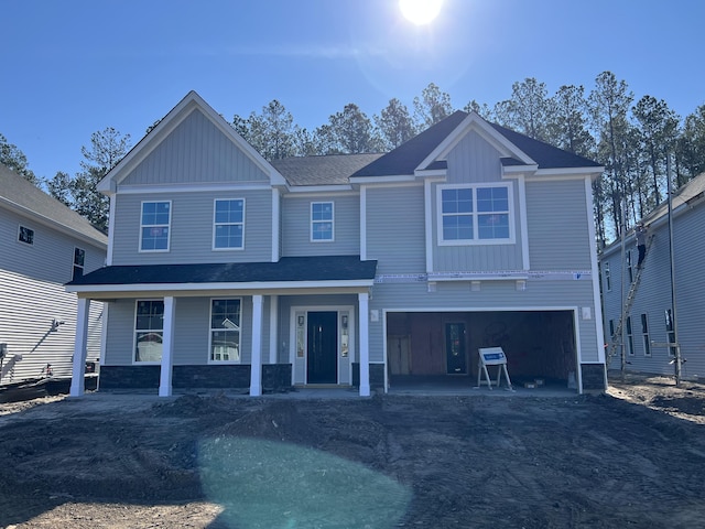 view of front of house featuring an attached garage, a porch, aphalt driveway, and board and batten siding