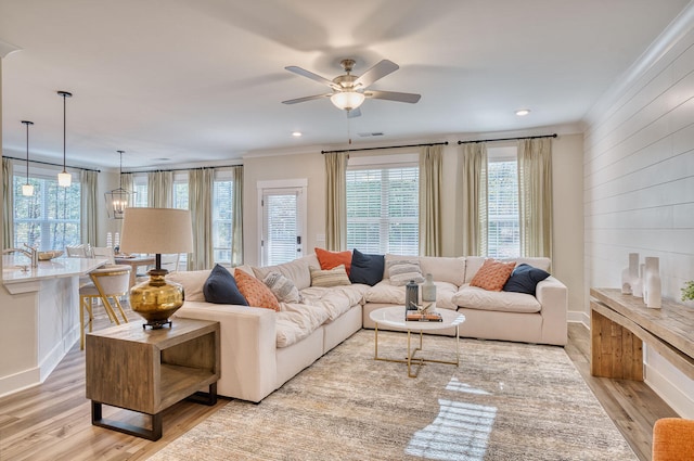 living room with visible vents, baseboards, a ceiling fan, light wood finished floors, and crown molding