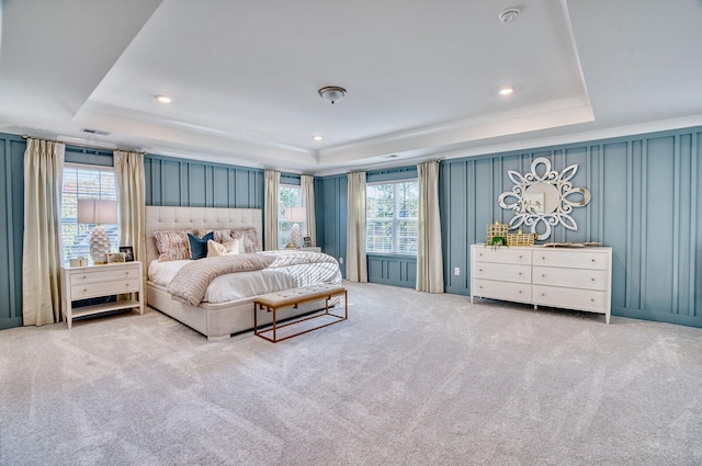 carpeted bedroom with a tray ceiling, visible vents, a decorative wall, and recessed lighting