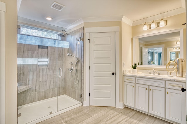 full bath with a stall shower, vanity, visible vents, and ornamental molding