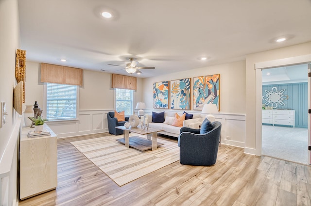 living room with a ceiling fan, a wainscoted wall, light wood-style flooring, a decorative wall, and recessed lighting