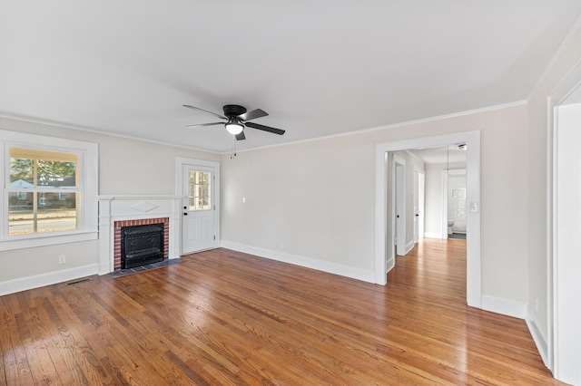 unfurnished living room with hardwood / wood-style floors, ceiling fan, ornamental molding, and a fireplace