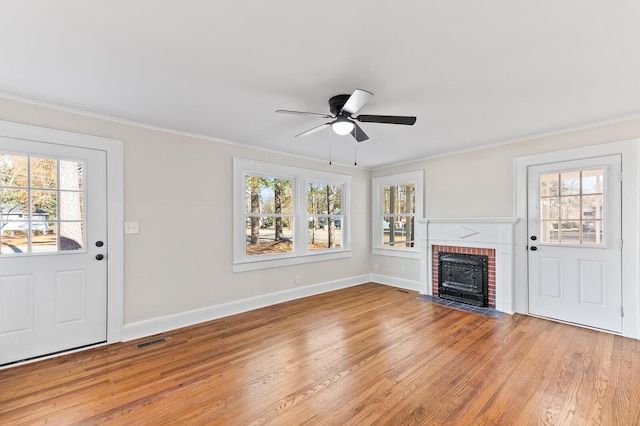 unfurnished living room featuring ceiling fan, light hardwood / wood-style flooring, ornamental molding, and a brick fireplace