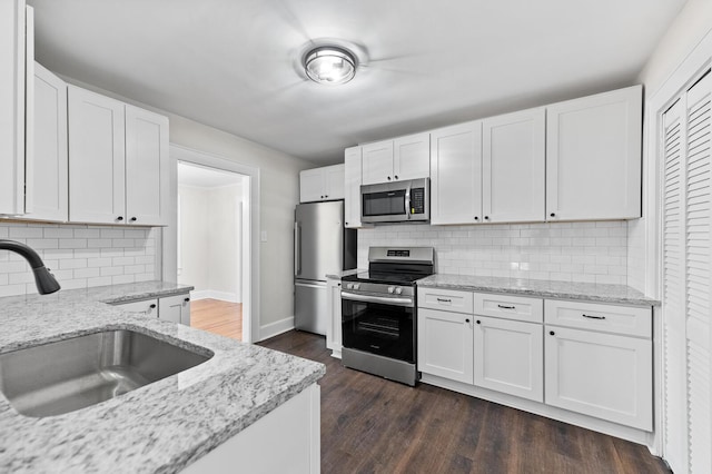 kitchen featuring light stone countertops, appliances with stainless steel finishes, dark wood-type flooring, sink, and white cabinets