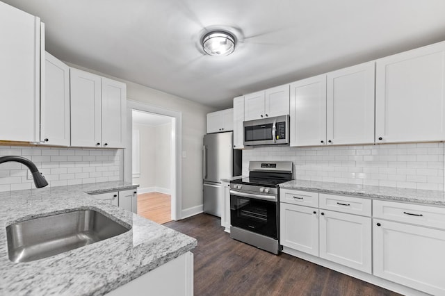 kitchen featuring light stone countertops, dark hardwood / wood-style flooring, stainless steel appliances, sink, and white cabinets