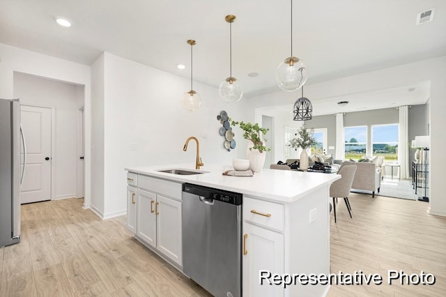 kitchen featuring hanging light fixtures, stainless steel appliances, an island with sink, white cabinets, and light wood-type flooring