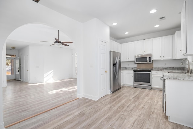 kitchen with stainless steel appliances, ceiling fan, sink, light hardwood / wood-style floors, and white cabinetry