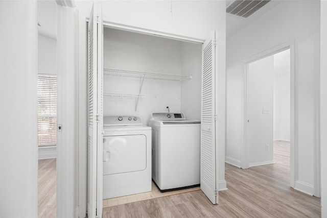 laundry room with washing machine and dryer and light hardwood / wood-style flooring