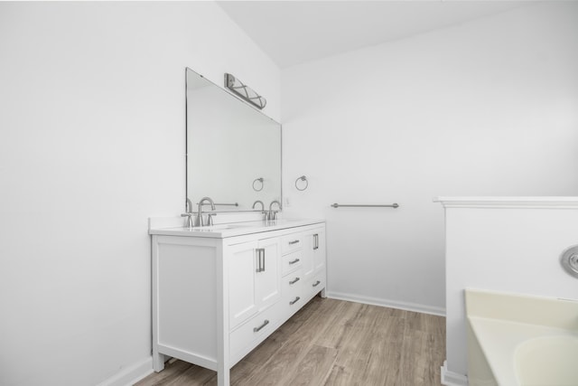 bathroom with a bath, hardwood / wood-style floors, and vanity