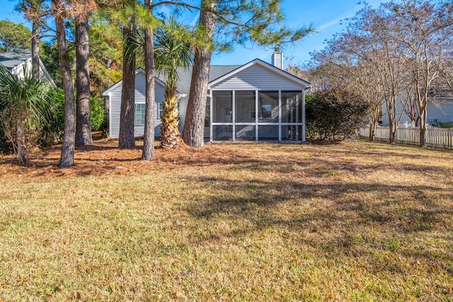 back of house featuring a lawn and a sunroom