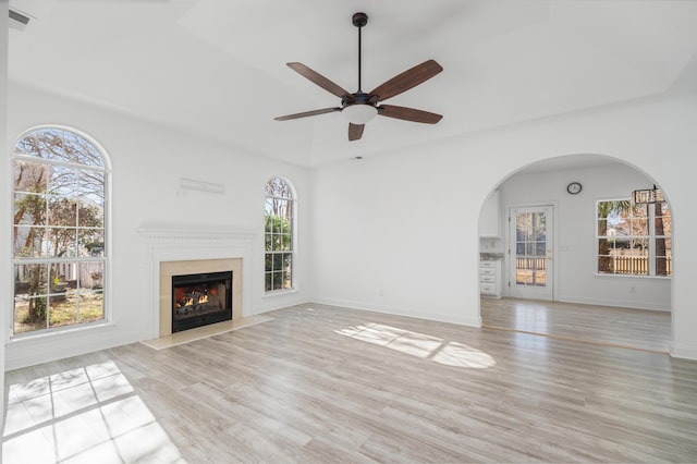 unfurnished living room with light wood-type flooring, a wealth of natural light, and ceiling fan