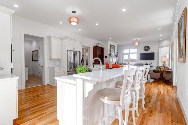 kitchen featuring white cabinetry, a kitchen bar, light wood-type flooring, pendant lighting, and stainless steel refrigerator with ice dispenser