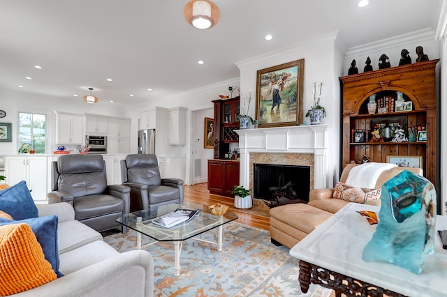 living room with a premium fireplace, light hardwood / wood-style floors, and ornamental molding