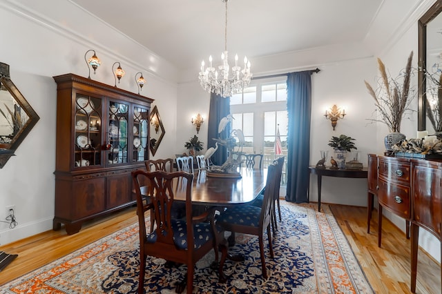 dining space with a chandelier, light hardwood / wood-style floors, and crown molding