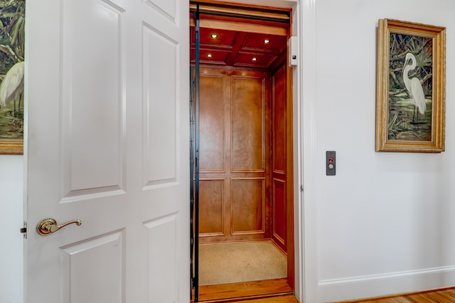 hall with light hardwood / wood-style floors and elevator