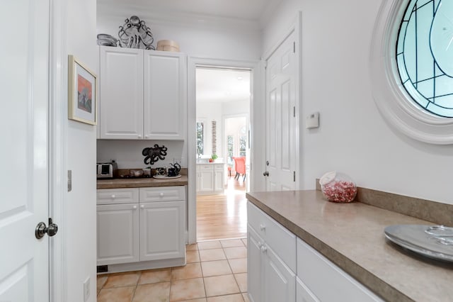 kitchen featuring ornamental molding, white cabinets, and light tile floors