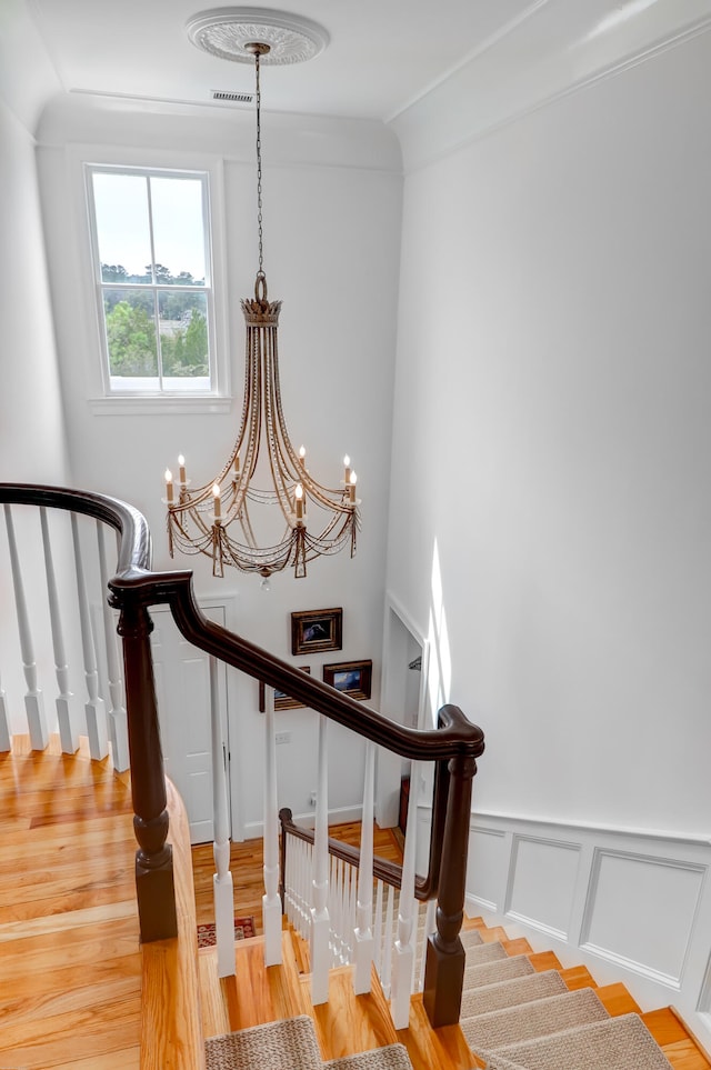 staircase with an inviting chandelier and light hardwood / wood-style floors