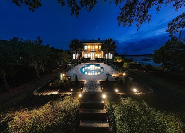 pool at twilight featuring a patio area