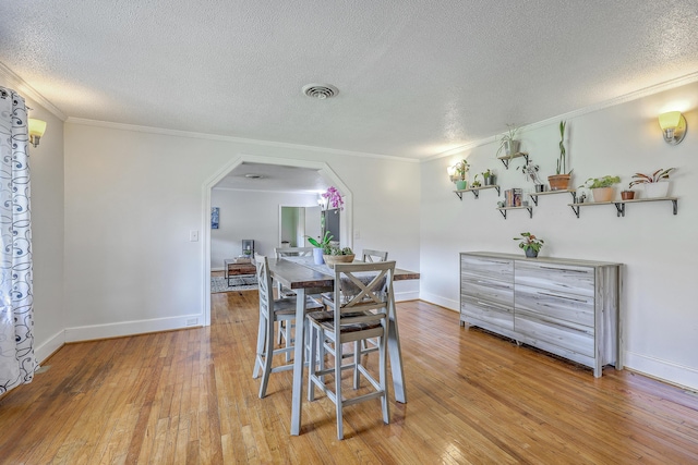 1314 Cooper Store Rd, Moncks Corner, SC 29461 - dining space featuring arched walkways, light wood-type flooring, a textured ceiling, crown molding, and baseboards