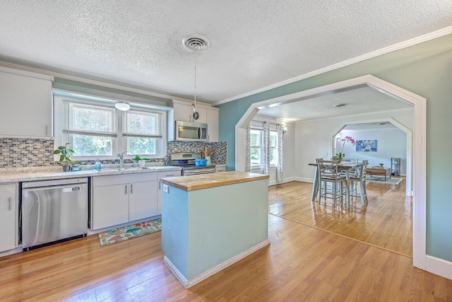 1314 Cooper Store Rd, Moncks Corner, SC 29461 - kitchen featuring stainless steel appliances, wooden counters, arched walkways, a sink, and ornamental molding
