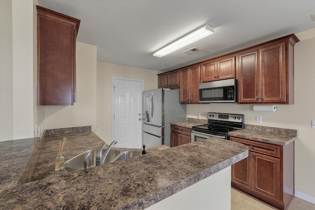 kitchen with visible vents, dark countertops, a peninsula, stainless steel appliances, and a sink