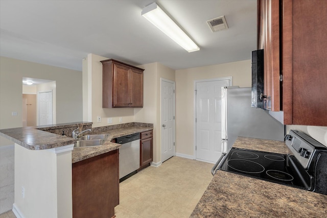 kitchen featuring baseboards, visible vents, appliances with stainless steel finishes, a peninsula, and a sink