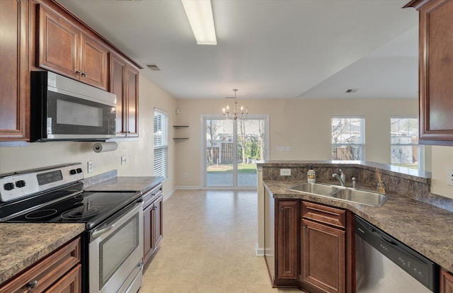 kitchen featuring visible vents, a peninsula, stainless steel appliances, a chandelier, and a sink