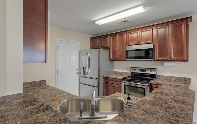 kitchen featuring dark stone countertops, visible vents, stainless steel appliances, and a sink