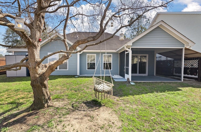 rear view of house featuring a patio, a shingled roof, and a lawn