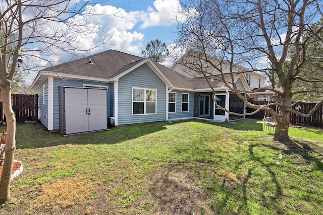 rear view of property with a fenced backyard, a lawn, and roof with shingles