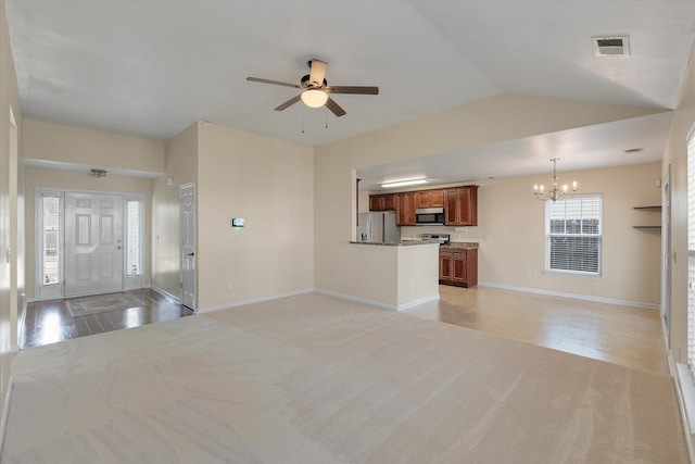 unfurnished living room with lofted ceiling, light carpet, ceiling fan with notable chandelier, visible vents, and baseboards