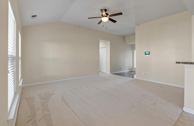 carpeted empty room with vaulted ceiling, baseboards, visible vents, and a ceiling fan