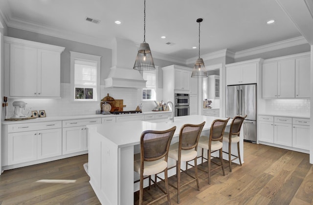 1098 Reserve Ln, Awendaw, SC 29429 - kitchen featuring appliances with stainless steel finishes, decorative backsplash, a center island with sink, white cabinetry, and light countertops