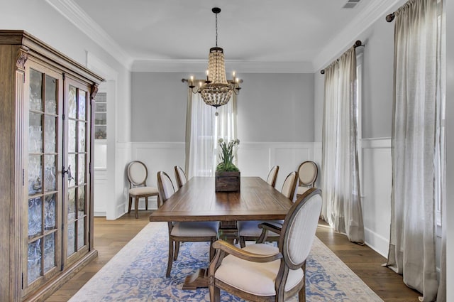 1098 Reserve Ln, Awendaw, SC 29429 - dining room with a chandelier, wainscoting, a decorative wall, dark wood-style floors, and crown molding