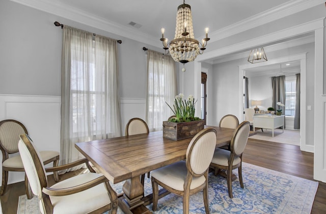 1098 Reserve Ln, Awendaw, SC 29429 - dining room with a chandelier, wainscoting, dark wood-style floors, crown molding, and a decorative wall