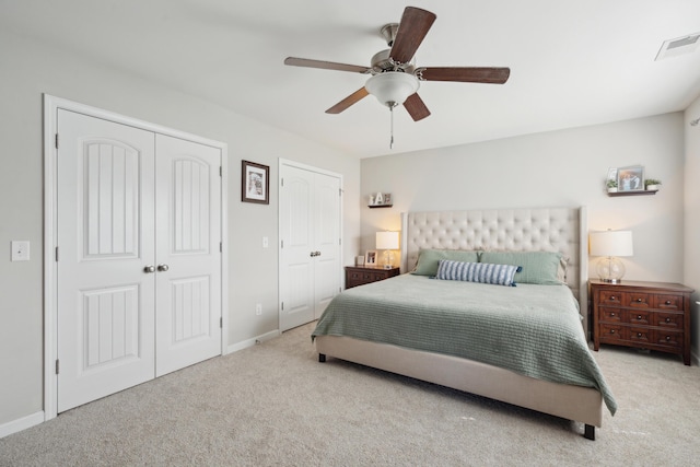 bedroom featuring carpet floors, visible vents, baseboards, and two closets