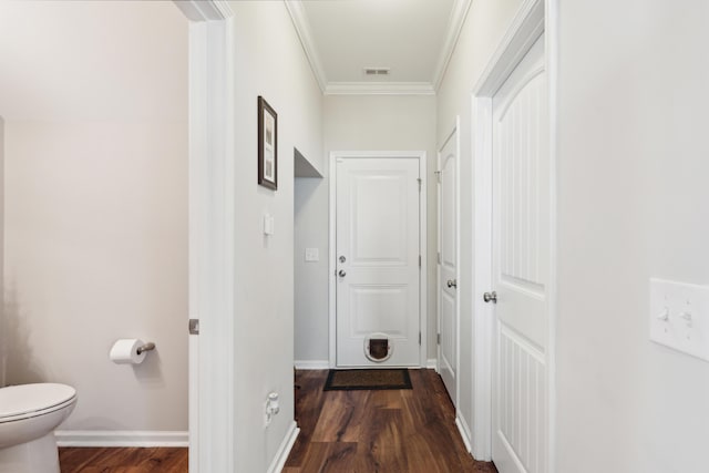 corridor with crown molding, wood finished floors, visible vents, and baseboards