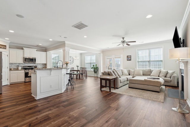 living area with crown molding, visible vents, dark wood-style flooring, and recessed lighting