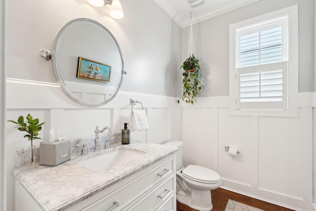 bathroom featuring vanity, ornamental molding, hardwood / wood-style floors, and toilet