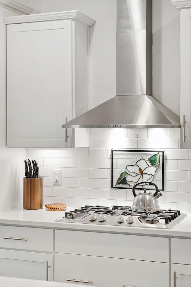 kitchen featuring tasteful backsplash, white cabinetry, gas stovetop, and wall chimney exhaust hood