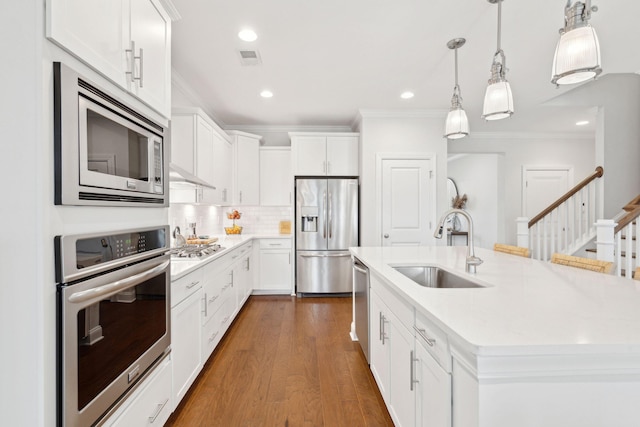 kitchen with white cabinetry, sink, hanging light fixtures, a kitchen island with sink, and stainless steel appliances