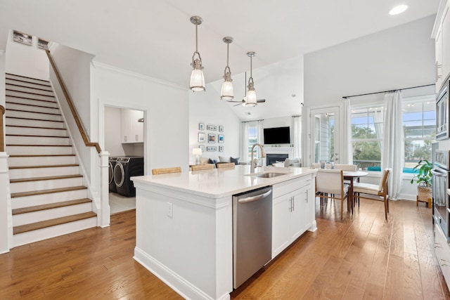 kitchen with sink, white cabinetry, hanging light fixtures, stainless steel appliances, and an island with sink