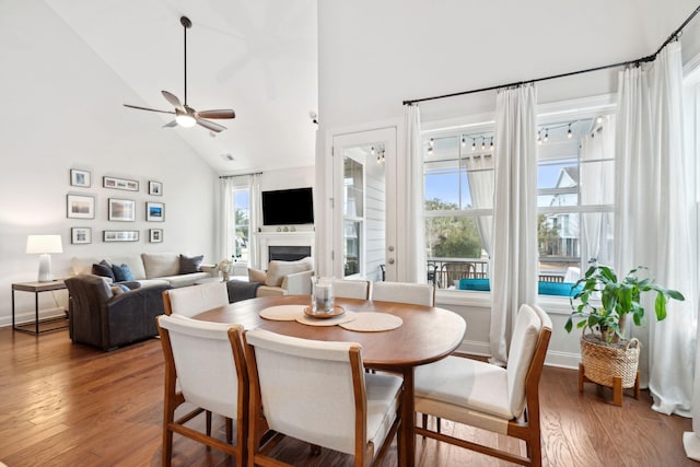 dining area with ceiling fan, wood-type flooring, and high vaulted ceiling