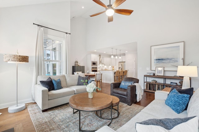 living room featuring high vaulted ceiling, ceiling fan, and light wood-type flooring