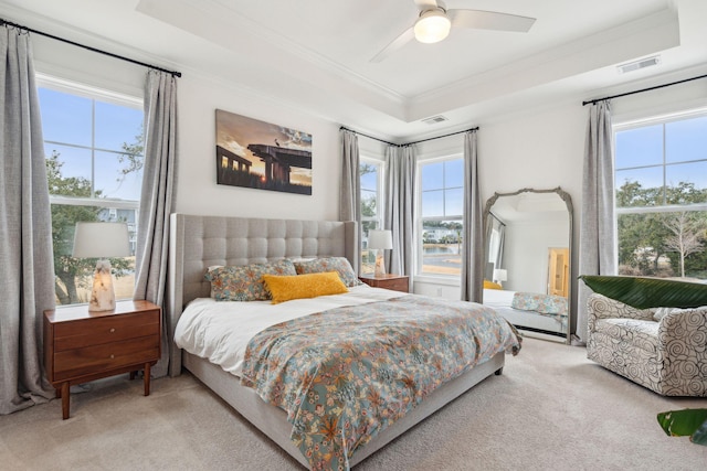 bedroom featuring ceiling fan, ornamental molding, a tray ceiling, and light colored carpet