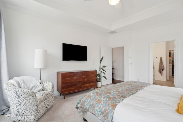 carpeted bedroom with crown molding, a tray ceiling, ensuite bath, and ceiling fan