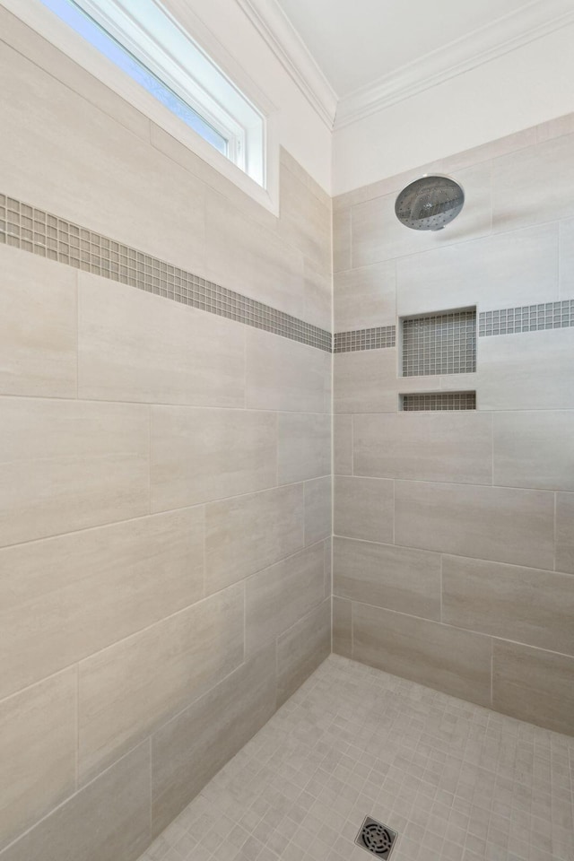 bathroom with ornamental molding and a tile shower