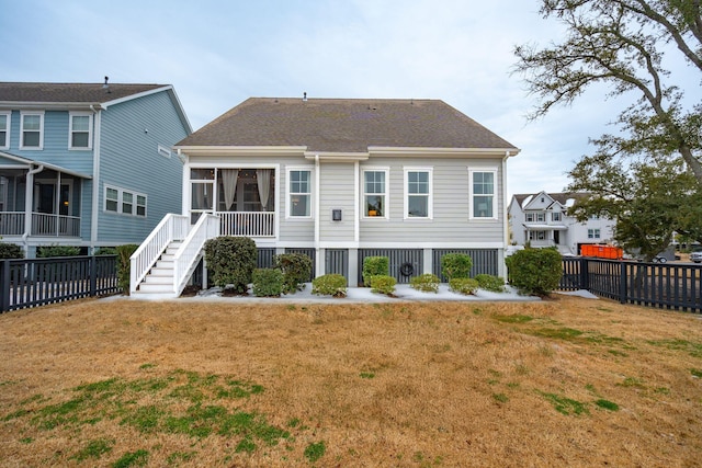 back of property with a sunroom and a lawn