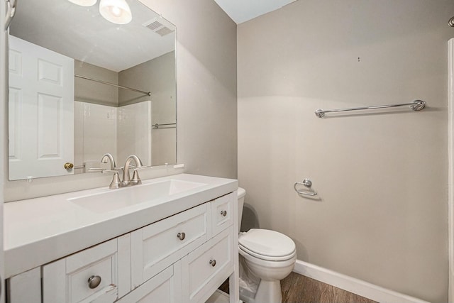 bathroom featuring hardwood / wood-style flooring, vanity, walk in shower, and toilet